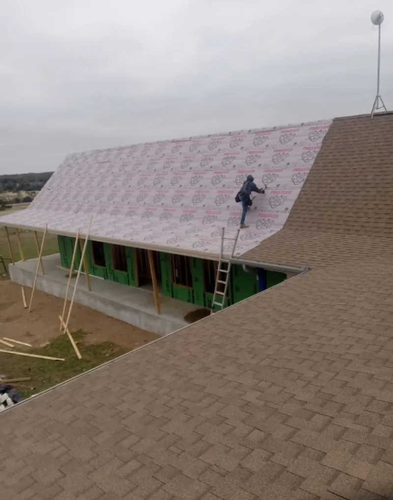 Worker preparing underlayment for a metal roof installation in Kodiak